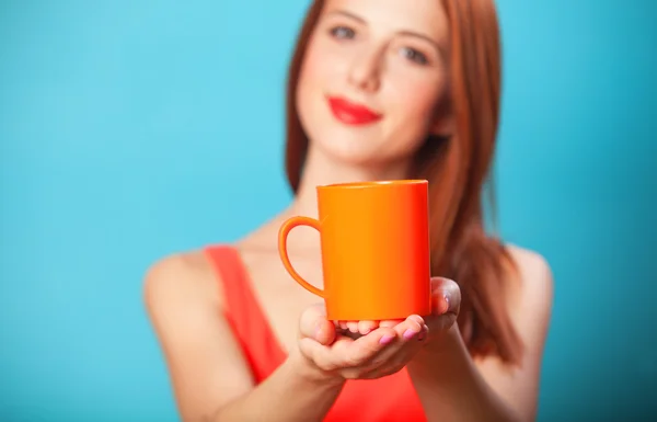 Redhead women with cup on blue background. — Stock Photo, Image