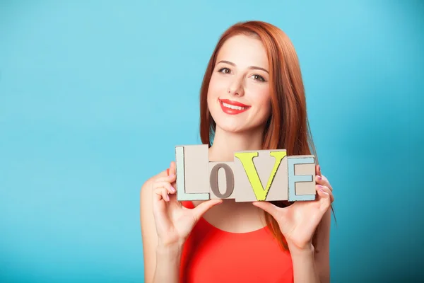 Feliz pelirroja de las mujeres con la palabra Amor sobre fondo azul . —  Fotos de Stock