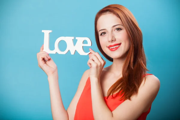 Gelukkig roodharige vrouwen met woord liefde op blauwe achtergrond. — Stockfoto