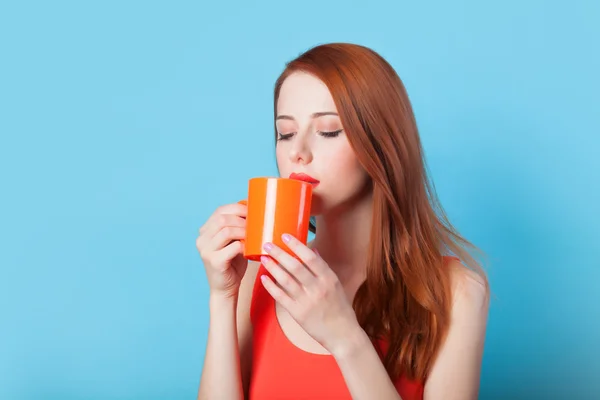 Redhead women with cup on blue background. — Stock Photo, Image