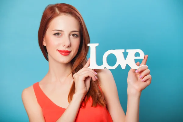 青の背景に愛という言葉で幸せな赤毛の女性. — ストック写真