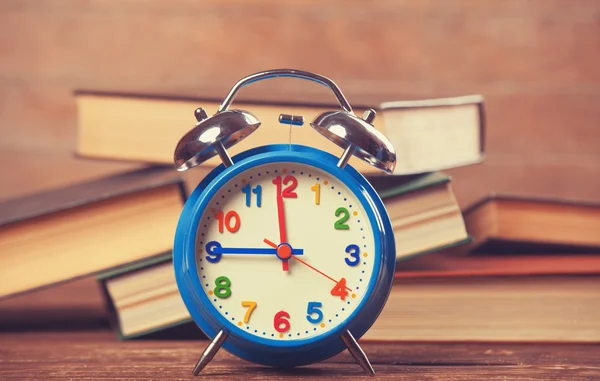 Wekker en boeken over houten tafel. — Stockfoto