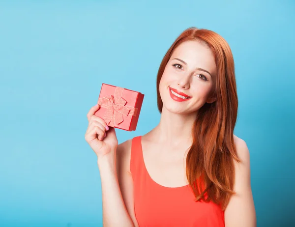 Donne rosse sorridenti con regalo su sfondo blu . — Foto Stock