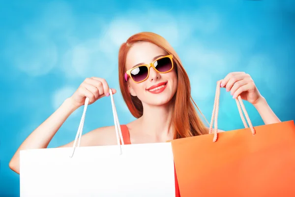 Style redhead women holding shopping bags on blue background. — Stock Photo, Image