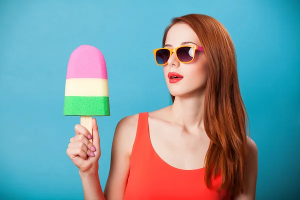 Redhead girl with toy ice cream on blue background. — Stock Photo, Image