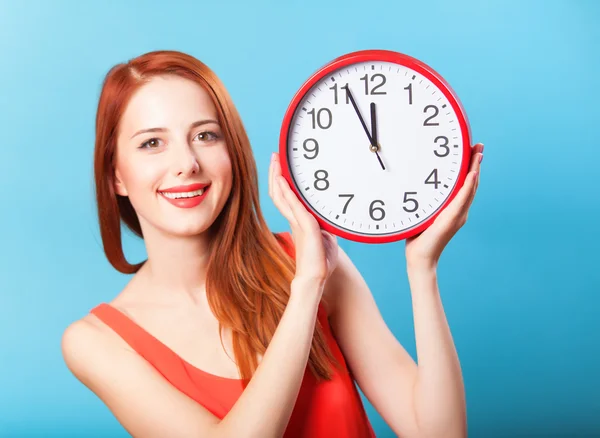 Redhead girl with huge clock on blue background. — Stock Photo, Image