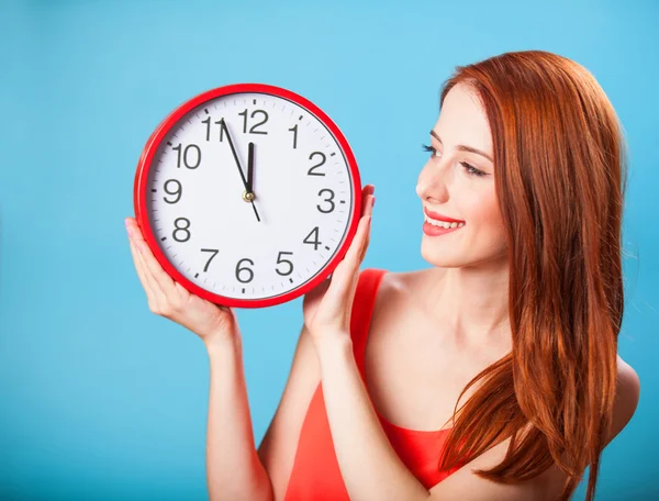 Ragazza rossa con enorme orologio su sfondo blu . — Foto Stock