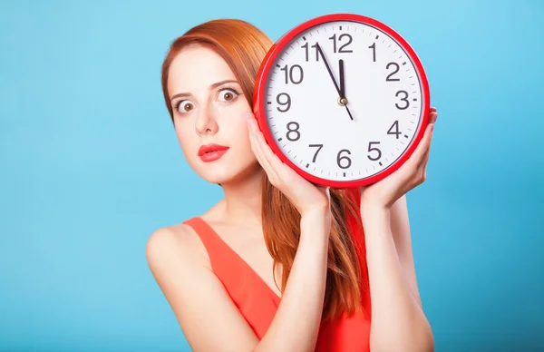 Redhead girl with huge clock on blue background. — Stock Photo, Image