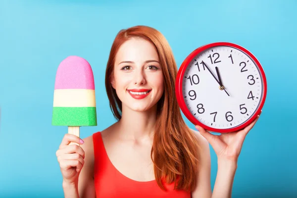 Ragazza rossa con gelato giocattolo e orologio enorme sul backgroun blu — Foto Stock