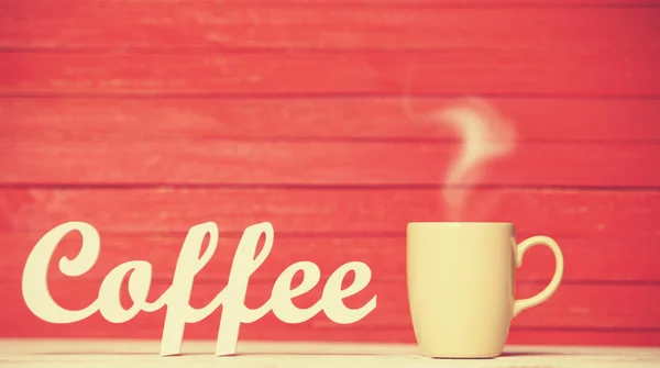 Abstrakte Holzwort Kaffee mit Tasse auf rotem Holzhintergrund. — Stockfoto