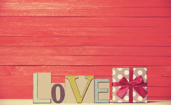 Lilla gåva och ordet kärlek på träbord. — Stockfoto