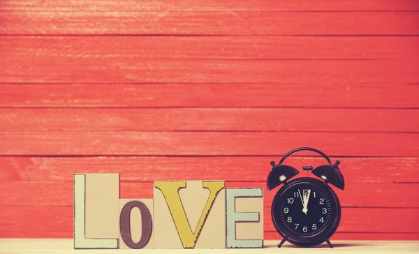 Alarm clock and wooden word Love. — Stock Photo, Image