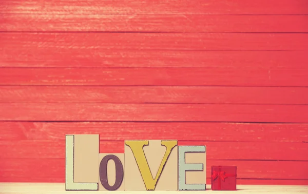 Μικρό δώρο και την λέξη αγάπη στο ξύλινο τραπέζι. — Φωτογραφία Αρχείου
