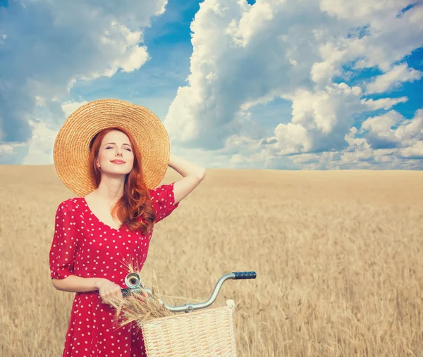 Рыжая крестьянка с велосипедом на пшеничном поле . — стоковое фото