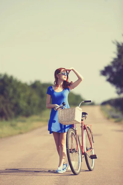 Roodharige meisje met fiets op landweg. — Stockfoto