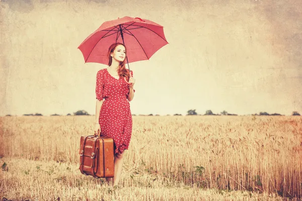 Redhead girl with umbrella and suitcase at outdoor — Stock Photo, Image