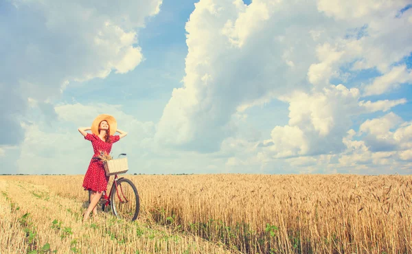 Redhead boerenmeisje met fiets op tarweveld. — Stockfoto