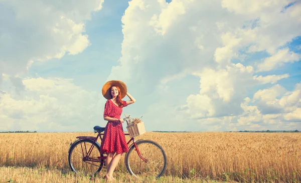 Redhead peasant girl with bicycle on wheat field. — Stock Photo, Image