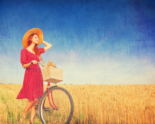 Rödhårig bondflicka med cykel på vete fält. — Stockfoto
