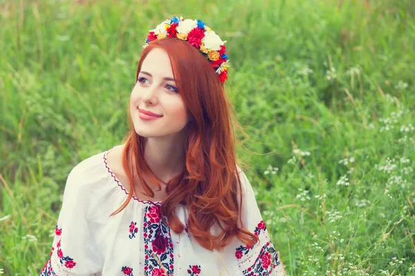 Menina ruiva em roupas ucranianas nacionais na grama verde . — Fotografia de Stock