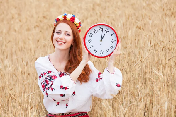 Redhead girl in national ukrainian clothes with clock on the whe — Stock Photo, Image