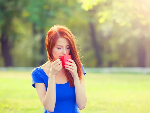 Redhead girl with orange cup at outdoor — Stock Photo, Image