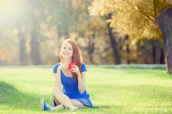 Menina ruiva com copo laranja ao ar livre — Fotografia de Stock