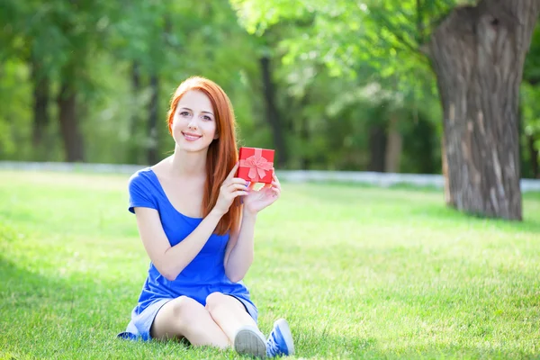 Γυναίκες κοκκινομάλλα με δώρο σε πράσινο γρασίδι. — Φωτογραφία Αρχείου