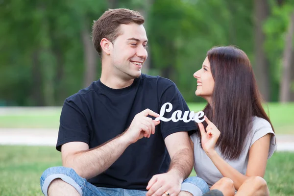 Teen couple with word Love in the park — Stock Photo, Image