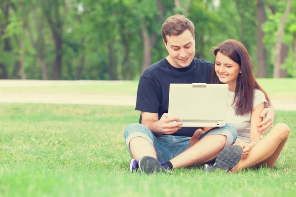 Teen par med anteckningsboken i parken — Stockfoto