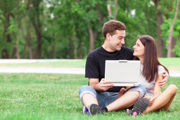 Teen couple with notebook in the park — Stock Photo, Image