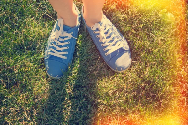 Blaue Turnschuhe auf gesättigtem grünen Gras. Foto im alten Farbbild — Stockfoto