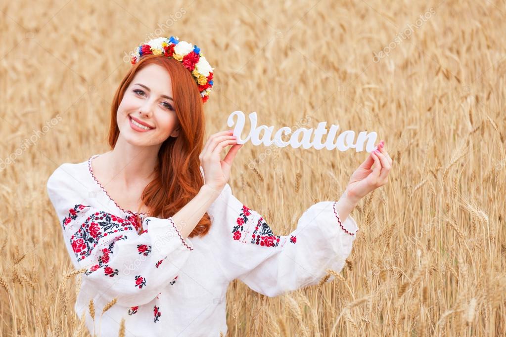 Redhead girl in national ukrainian clothes with wooden word Vaca