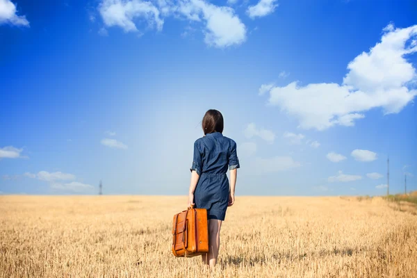 Brunette girl  withsuitcase on wheat field. — Stock Photo, Image