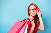 Vöröshajú lány a bevásárló szatyrok-kék háttér.