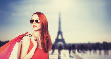 Paris arka plan üzerinde alışveriş torbaları ile Kızıl saçlı kadın.