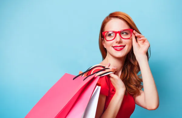 Fille rousse avec des sacs à provisions sur fond bleu . — Photo