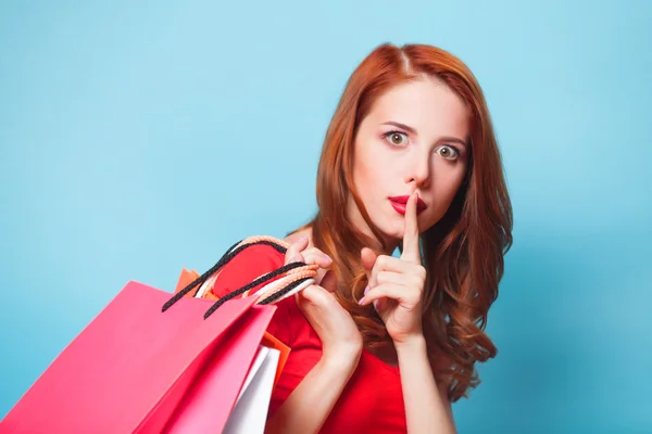 Fille rousse avec des sacs à provisions sur fond bleu . — Photo