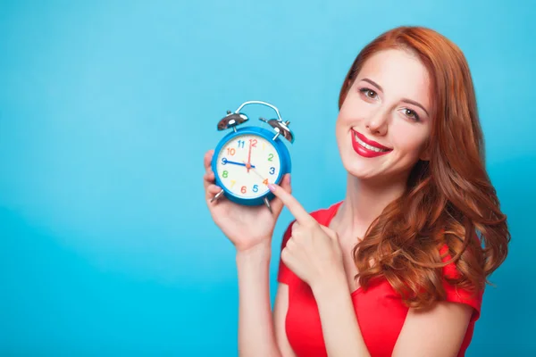 Redhead girl with alarm clock on blue background. — Stock Photo, Image