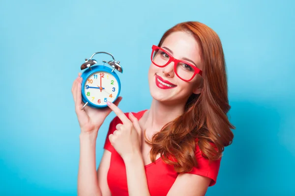 Redhead girl with alarm clock on blue background. — Stock Photo, Image