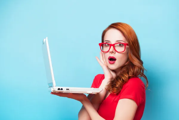 Rothaarige Mädchen mit Laptop auf blauem Hintergrund. — Stockfoto