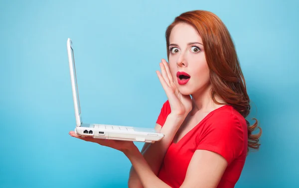 Pelirroja chica con portátil sobre fondo azul . — Foto de Stock