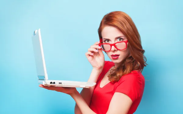 Rothaarige Mädchen mit Laptop auf blauem Hintergrund. — Stockfoto