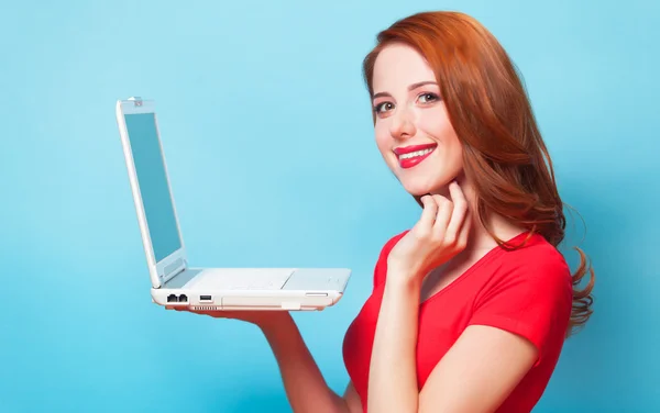 Rothaarige Mädchen mit Laptop auf blauem Hintergrund. — Stockfoto