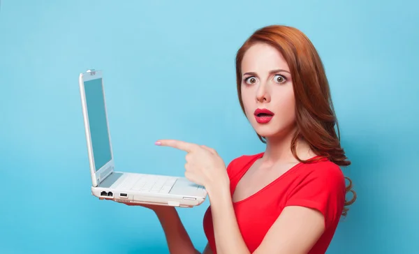 Rödhårig tjej med laptop på blå bakgrund. — Stockfoto