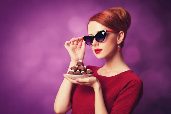 Redhead women with candy on violet background. — Stock Photo, Image