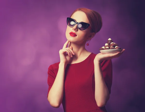 红发女性用紫色背景上的糖果. — 图库照片