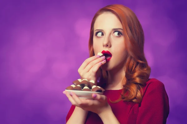 Roodharige vrouwen met suikergoed op violette achtergrond. — Stockfoto