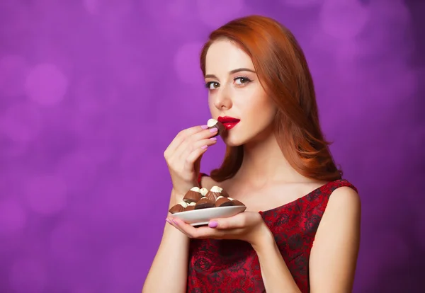 红发女性用紫色背景上的糖果. — 图库照片