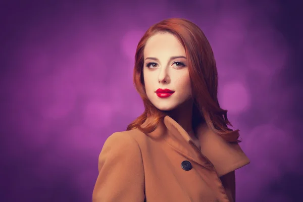 Redhead women in coat on vilolet background. — Stock Photo, Image